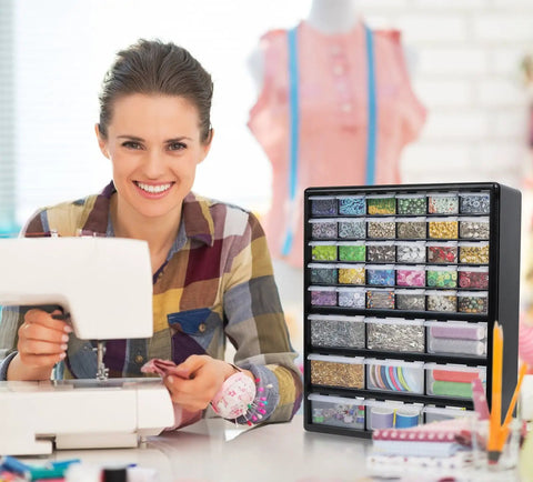 Woman sewing with Ultimate Screw Organizer And Hardware Storage Cabinet With 39 Drawers beside her, filled with crafts.