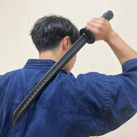 Man practicing with Polypropylene Short Practice Samurai Training Sword 24-Inch With Black Saya Scabbard, holding sword overhead.