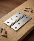 24 Pack 3.5 Inch Stainless Steel Folding Butt Hinges With Mounting Screws on wood surface, quiet operation for cabinets and furniture