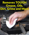 White heavy-duty cleaning towel used to wipe car battery terminals (hand close-up)