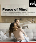 Mother and daughter smiling on a couch in a modern living room, promoting the Rely Essentials smoke alarm with photoelectric sensor.