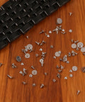 100 Piece Watch Screw Set With Micro Battery Clamp Screws, Stainless Steel Assortment for watchmaking and repair on wooden surface