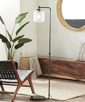 Dope Industrial Arc Floor Lamp With Glass Shade And Black Metal Body, 61 Inch Tall in a modern living room corner
