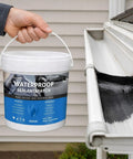 Big Time Roof Saver Black Waterproof Rubber Sealant For Flat And Metal Roofs With Flexible Crack Bridge that Moves With Building Shifts and Locks Out Water Damage For Good Without Any Headaches held over a roof gutter.