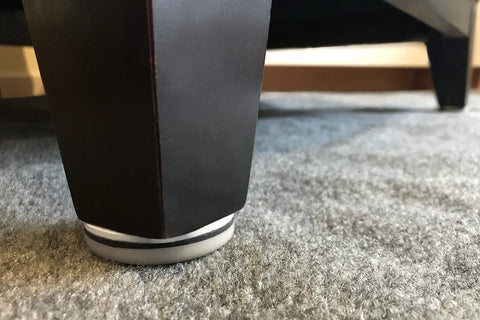 Close-up of furniture leg with Four Pack Nail On 1 Inch Swivel Furniture Glides With Low Friction Base installed on carpet.