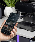 Next Level Semi Automatic Espresso Machine With Built In Grinder Steam Frother Featuring Italian Made 15 Bar Pump For Straight Up Perfect Shots Plus Wifi Connected Custom Brewing In Slick Black with smartphone app showing features.