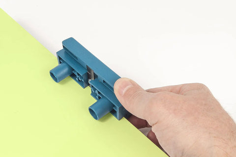 Hand holding AU93 Edge Banding Trimmer With Dual Edge Cutting And Scraper trimming a yellow edge on wood laminate.