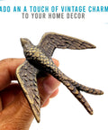 Close-up of hand holding a bird design handle from Vintage Cast Iron Closet Door Pull Handles In Bronze Finish With Delicate Bird Design Set Of 2.