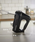 Black Six Speed Easy Storage Hand Mixer With Five Attachments And Case on kitchen countertop, dimensions labeled.
