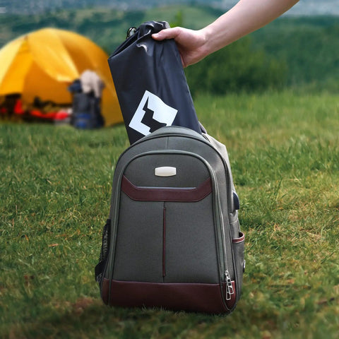 Hand placing folded Ultralight Aluminum Camping Side Table With Carry Bag into backpack on grass near yellow tent