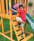 Children climbing a rock wall ladder on a weatherproof wooden swing set for backyard with UV and mold protection, durable pre-treated lumber.