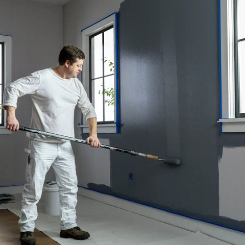 Painter using ProGrade Painter Tape With PaintBlock Technology Blue 1.5 Inch Wide Multi Surface Masking Tape for sharp lines on wall.