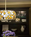 Decorative hanging light fixture with circular patterns in dining room set against a dark cabinet background.