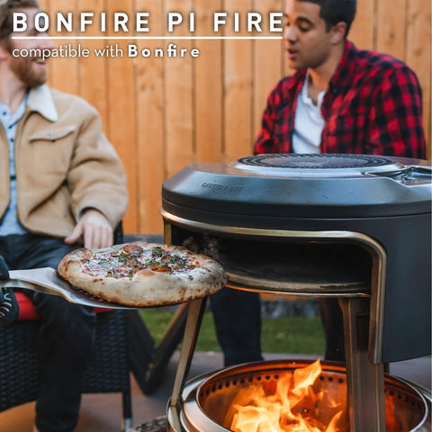 Bonfire Pi Fire Pizza Oven Accessory For Fire Pit with pizza stone baking a pizza, showing wood-burning flames below.