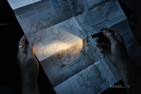 Compact LED Flashlight With 1-Cell AAA Battery 47 Lumens 46m Beam illuminating a map in dark scene, highlights adjustable beam.