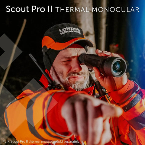 Person using Scout Pro II thermal monocular in outdoor setting, wearing orange gear, pointing with hand.