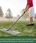 Person using Pro Grade Lawn Leveling Rake With Stainless Steel Pole, Heavy Duty 36x10 Inch Leveller on uneven golf course terrain.