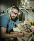 Man wearing Black Frame Safety Glasses With Clear Anti Fog Lenses And LED Temples, Ventilated Design, working in workshop.
