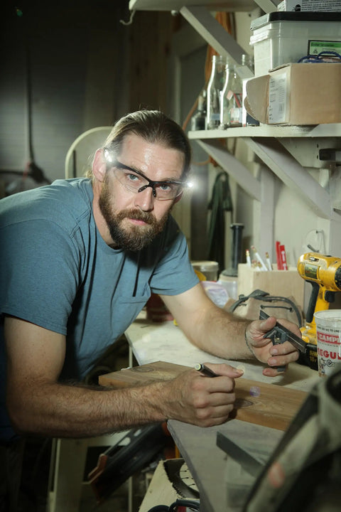 Man wearing Black Frame Safety Glasses With Clear Anti Fog Lenses And LED Temples, Ventilated Design, working in workshop.