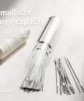 Clear tube filled with metal sewing needles, next to a spool of thread on white background.