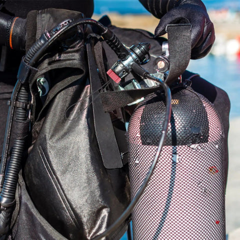 Diver holding scuba gear with red air tank valve cover dust plug protector cap for scuba regulators and threaded gas bottles