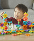 Child playing with 101 Piece Gear Building Set For Kids So They Can Build Twisting Gardens While Learning Cause Effect Sequencing And Early Engineering Hands On STEM Construction Toy Montessori Inspired Kid Friendly Fine Motor Play And Educational Engineering Gift on a table.