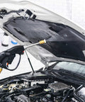 Black rotating turbo nozzle attached to pressure washer spray gun, cleaning car hood; brass connector visible.