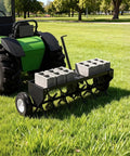 48-Inch Tow Behind Plug Aerator with 150 lb weight tray, 24 steel tines, inflatable wheels, attached to lawn tractor in field