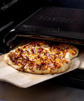 Gravity Series Outdoor Pizza Oven Accessory Insert With Ceramic Stone And Stainless Interior in use, baking a pizza.