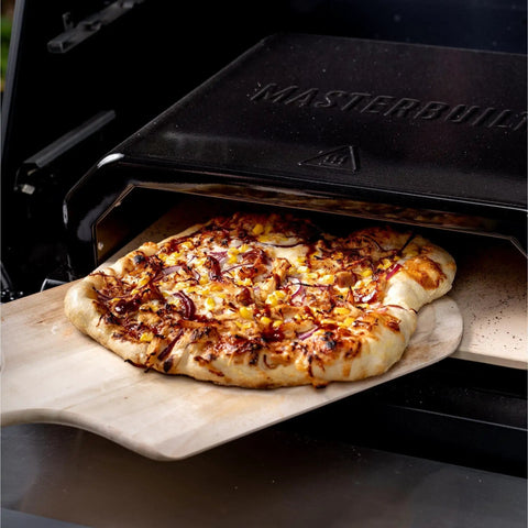 Gravity Series Outdoor Pizza Oven Accessory Insert With Ceramic Stone And Stainless Interior in use, baking a pizza.