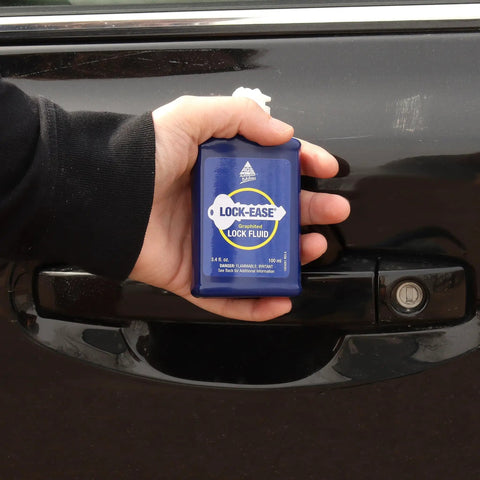 Person holding Lock-Ease lock fluid by car door for lubrication and maintenance, 3.5 oz bottle, used for locks and hinges.
