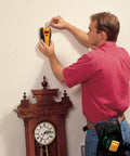 Person using Slick All In One Stud Finder Pins Wood Metal And Live Ac Wires Fast With A Bright Lcd Screen on wall.