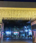 Warm White LED Icicle String Lights For Windows And Outdoor Spaces 16.4Ft 216 LEDs illuminating a covered walkway at night.