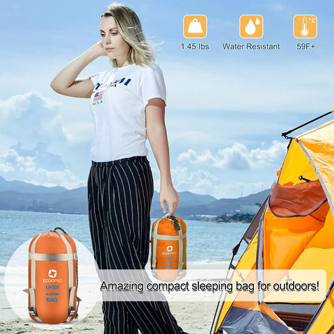 Person holding warm weather sleeping bag for outdoors portable waterproof and lightweight with compression sack, orange color.