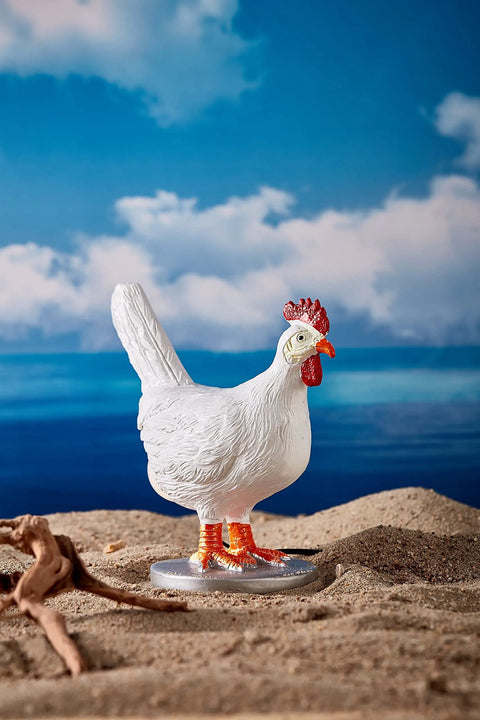 Decorative white chicken figure on sandy beach with ocean background