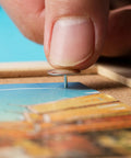Hand placing a Real Solid Silver Flat Head Thumb Tack on a bulletin board with a photo, great for office crafts.