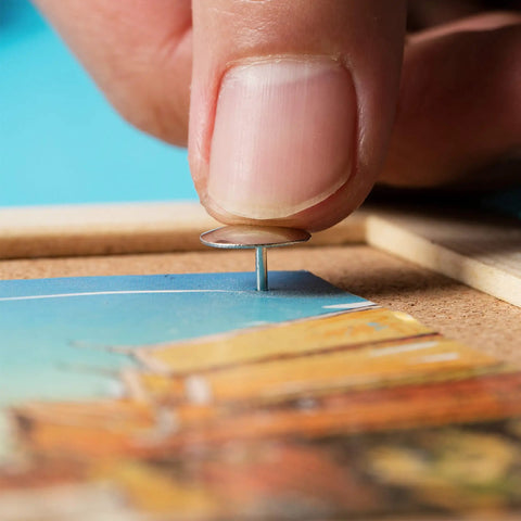 Hand placing a Real Solid Silver Flat Head Thumb Tack on a bulletin board with a photo, great for office crafts.