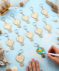 Color Your Own Hot Air Balloon Keychains Kit With 24 Wooden Blanks, 12 Styles, DIY Craft Set For Kids with a hand decorating one.