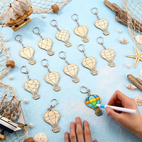 Color Your Own Hot Air Balloon Keychains Kit With 24 Wooden Blanks, 12 Styles, DIY Craft Set For Kids with a hand decorating one.