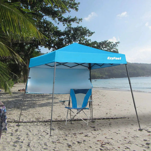 Grab-And-Go Ultra Compact Backpack Canopy Pop Up Shelter For Outdoor Adventures on a beach with a blue chair underneath.