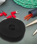 Reusable Adhesive Cable Ties For Desk Organization And Wire Management Cut To Fit Polyester Straps in black with tools and wires.
