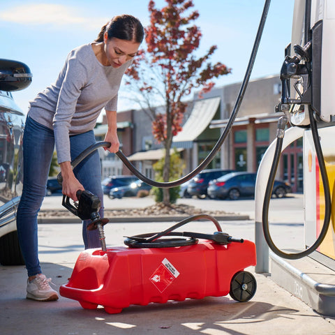 Woman refilling Flo N Go 14 Gallon Gas Caddy with 53 Liter Portable Fuel Tank, using built-in 10 foot hose at gas pump