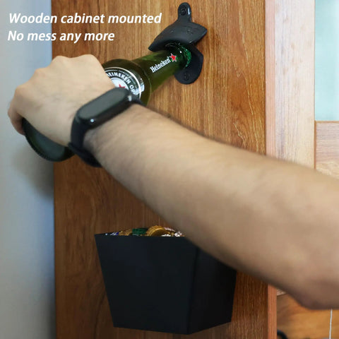Heavy Wall Mounted Beer Bottle Opener With Slick Stainless Steel Cap Catcher Bucket Rustproof Black Cast Iron Finish Keeps The Man Cave Clean And Looking Fresh, mounted on wooden cabinet.