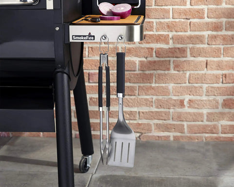 Precision 3 Piece Grilling Tool Set With Stainless Steel Tongs Spatula And Silicone Basting Brush hanging on the side of a grill