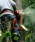 Arborist using chainsaw with Extended Bungee Chainsaw Strap With Long Snap Lanyard For Arborist Gear in forested area