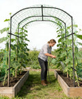 Woman tending plants under Metal Core Garden Arch Trellis For Climbing Plants Outdoor 87 Inch Tall 71 Inch Long 75 Inch Wide Archway Tunnel