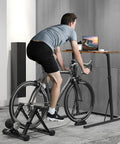 Man using Adjustable Standing Desk For Treadmills And Bike Workouts with laptop on bike in home gym office