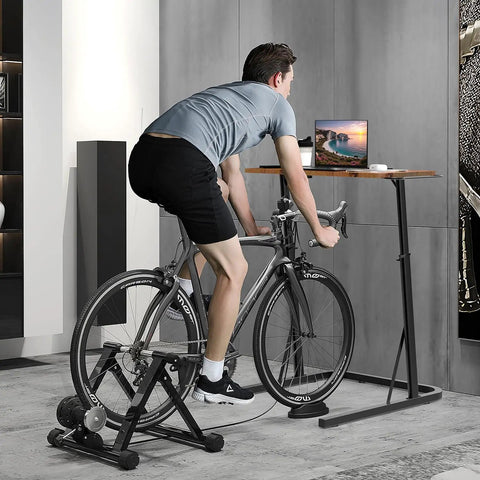 Man using Adjustable Standing Desk For Treadmills And Bike Workouts with laptop on bike in home gym office