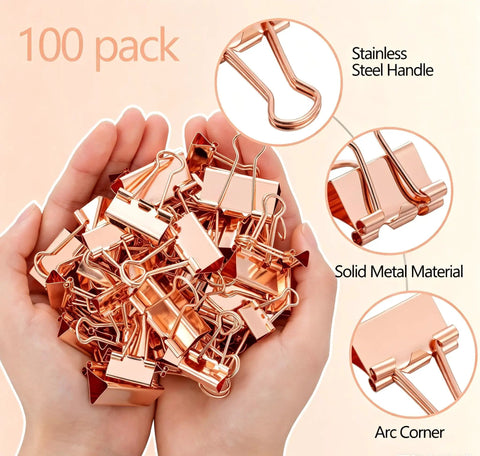 Hands holding rose gold binder clips, 100 pack, featuring stainless steel handles and solid metal material with arc corners.