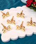 Set Of 8 Brass Bow Knobs For Cabinets And Drawers displayed on marble surface